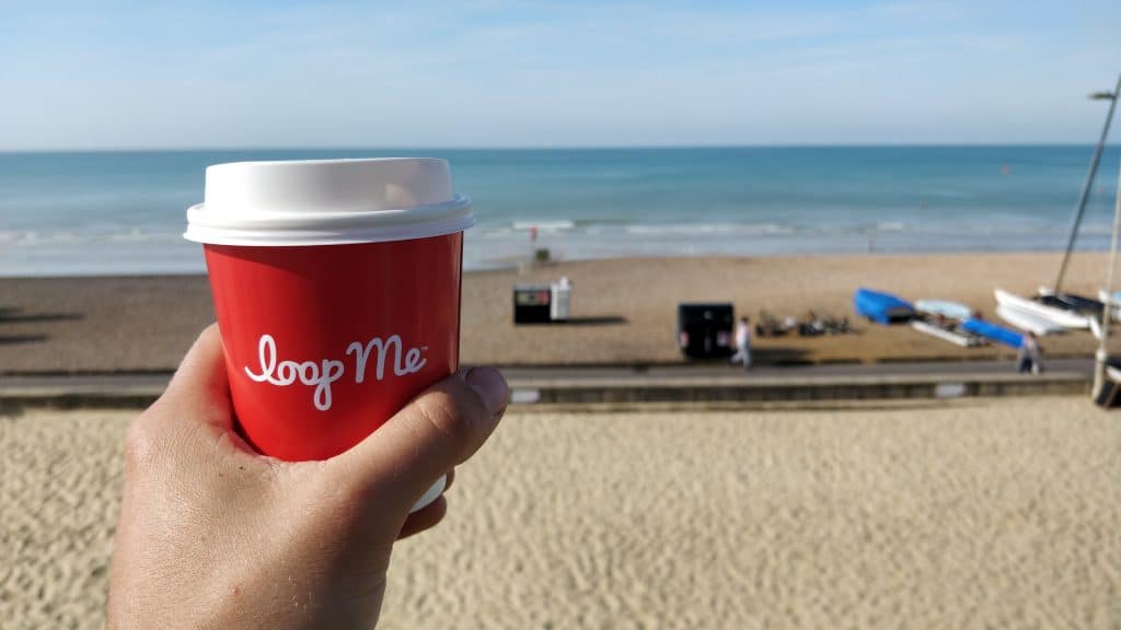 Customer holding red coffee cup at the beach