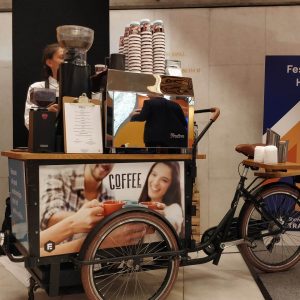 Barista stood by coffee bike at festival hall