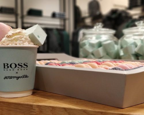 Hugo Boss coffee cup with cream and marshmallows next to a box of raspberry, lemon and blackcurrant macarons and Turkish Delight